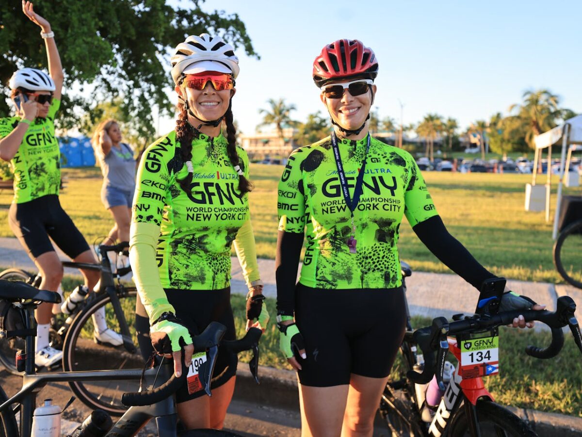 Two female cyclists pose at the GFNY World Championship in New York City park.