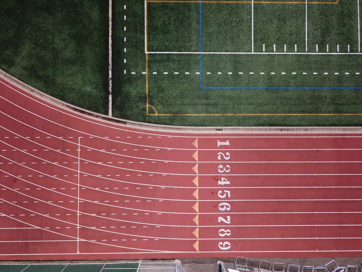 services-img-04 Aerial perspective of a red running track and adjacent green field.
